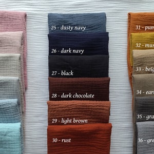 May include: A collection of folded fabric swatches in various colors, including dusty pink, dark navy, pumpkin, and grey. Each swatch is labeled with a number and color name, such as "27 - black" and "30 - rust."