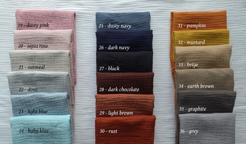 May include: A collection of folded fabric swatches in various colors, including dusty pink, dark navy, pumpkin, and grey. Each swatch is labeled with a number and color name, such as "27 - black" and "30 - rust."