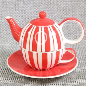 Könnte beinhalten: Ein rot-weiß gestreiftes Teeservice, bestehend aus einer Teekanne, einer Tasse und einer Untertasse. Die Teekanne hat eine runde Form mit Ausguss und Henkel. Die Tasse passt in die Teekanne, und das Set steht auf einer passenden Untertasse. Aus Keramik.
