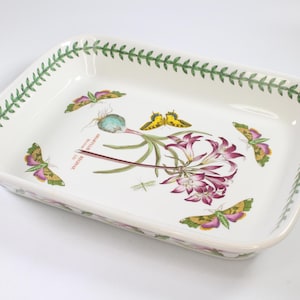 Puede incluir: Fuente rectangular de cerámica blanca con diseño botánico. La fuente presenta una ilustración floral y de mariposas en el centro, con un borde de hojas verdes. El diseño incluye acentos morados, amarillos y verdes.