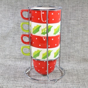 May include: A set of four ceramic mugs in a chrome metal holder. The mugs alternate between red with white polka dots and white with green holly leaf designs. Each mug has a different coloured handle: red and green.