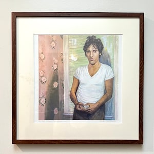 May include: A framed print of a man in a white t-shirt standing in a room with floral wallpaper. The text "To Our Father" and "Sarah Paul Smith" are visible at the bottom of the print.