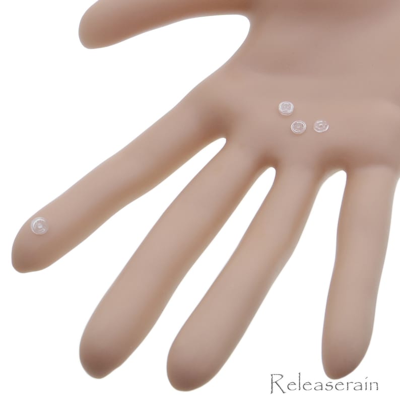 May include: Five clear plastic buttons, some with a raised center, are displayed on a light brown surface.