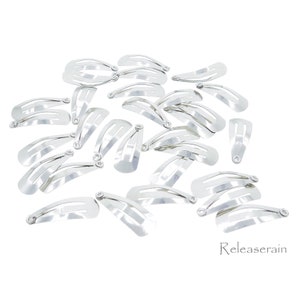 May include: A pile of silver metal hair clips. The clips are all the same size and shape, and they are arranged in a random pattern.