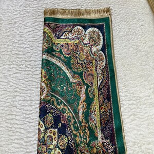Peut inclure: Un tapis de pri&egrave;re vert et or avec un motif persan traditionnel. Le tapis a une bordure &agrave; franges et est fait d'un tissu doux et luxueux.