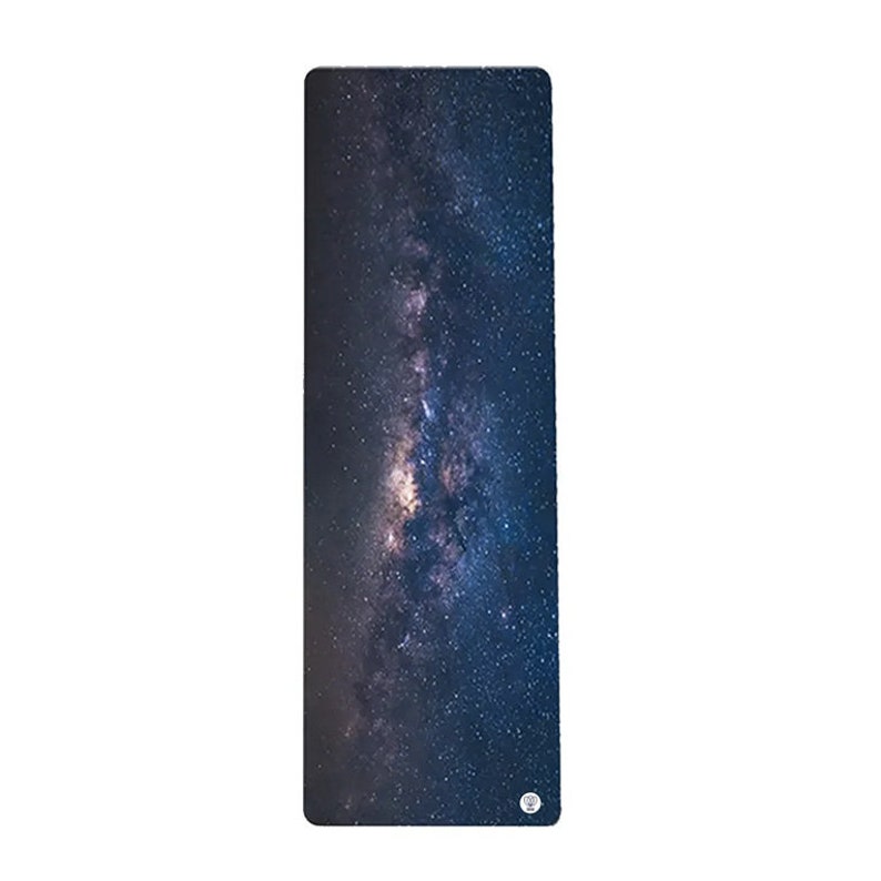 May include: A dark blue yoga mat with a printed image of the Milky Way galaxy. The mat has a subtle texture and a circular logo in the bottom right corner.