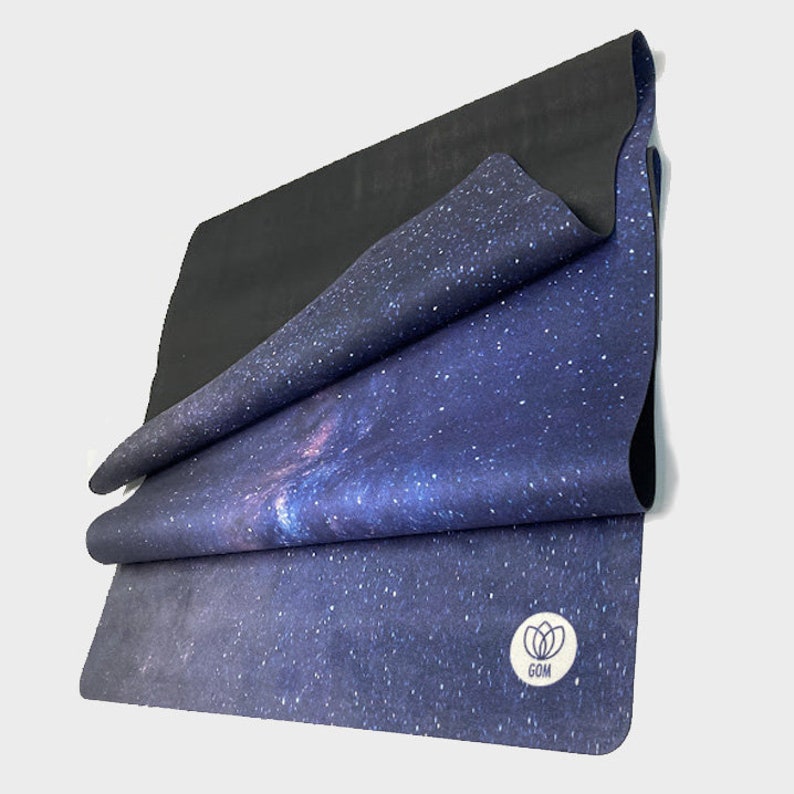 May include: A blue yoga mat with a galaxy print and a white logo that says "GOM". The mat is folded in thirds.