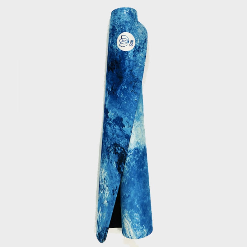 May include: A blue yoga mat with a white and blue marbled pattern. The mat is rolled up and has a white logo that says "GAM" on it.