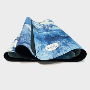 May include: A blue and white yoga mat with a blue and white lotus flower logo. The mat is rolled up and has a black edge.