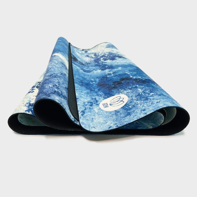 May include: A blue and white yoga mat with a blue and white lotus flower logo. The mat is rolled up and has a black edge.