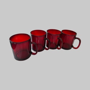 May include: Set of four red glass mugs with handles. The mugs are all the same size and shape.