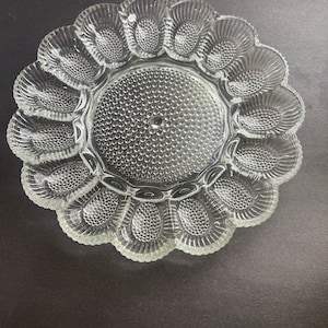 Puede incluir: Un plato para huevos de vidrio transparente con 12 compartimentos individuales. El plato tiene un diseño texturizado y en relieve.