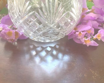 May include: A clear glass bowl with a cut crystal design. The bowl is sitting on a dark wood surface with a shadow cast from the bowl.