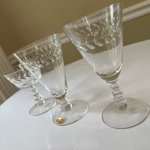 May include: Three clear glass wine glasses with etched leaf designs. The glasses have different shapes and sizes.
