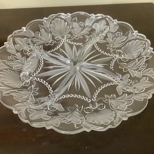 Puede incluir: Un plato de servir de vidrio transparente con cuatro secciones. El plato está decorado con un patrón floral y un borde de cuentas.