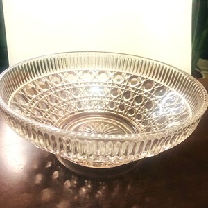 Puede incluir: Un cuenco de vidrio transparente con un patrón geométrico decorativo. El cuenco tiene una base ancha y redonda y un borde acampanado.