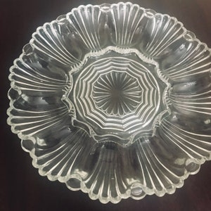 May include: A clear glass serving dish with a scalloped edge and a central, octagonal, patterned section. The dish has eight sections around the edge, perfect for serving individual portions.