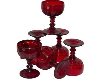 May include: Set of five red glass stemmed goblets with a ribbed design. The goblets are stacked on top of each other.