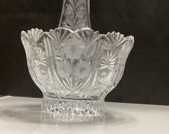 Könnte beinhalten: Ein klarer Glaskorb mit geschnittenem Glasdesign und einem Griff. Der Korb ist mit geätzten Blumenmustern verziert.