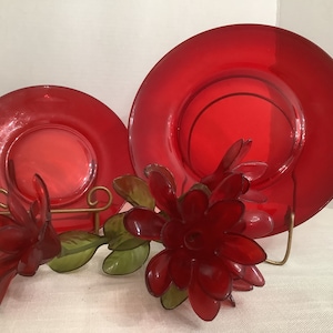 Könnte beinhalten: Drei rote Glasschalen in verschiedenen Größen, mit einer roten Plastikblume in der Mitte. Die Schalen stehen auf einem goldenen Ständer.