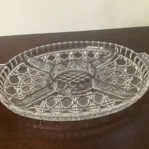 May include: A clear glass serving dish with five sections and a center dip. The dish has a decorative, criss-cross pattern.