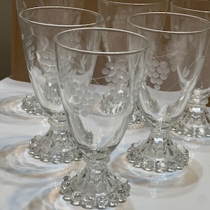 May include: Set of six clear glass goblets with a grapevine etched design and a beaded base.