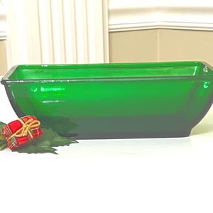 Könnte beinhalten: Eine große, smaragdgrüne Glasservierplatte mit rechteckiger Form und abgerundeten Kanten. Die Platte ist aus dickem Glas gefertigt und hat eine glänzende Oberfläche.