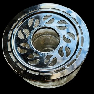 May include: Silver candle warmer with a glass base and a decorative metal top with a floral design. The top has the text "Candle Warmer" and "Patent Applied For" on it.
