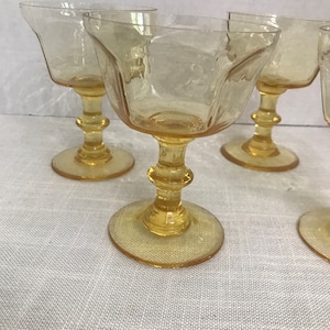 May include: Set of four amber glass stemmed drinking glasses with a faceted design. The glasses are clear and have a vintage look.