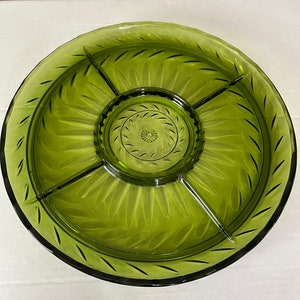 Puede incluir: Un plato de servir de vidrio verde con cuatro secciones divididas y un tazón central para salsas. El plato tiene un patrón decorativo grabado de hojas.