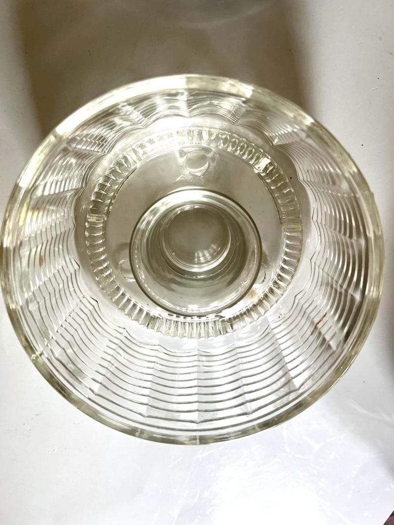 May include: A clear glass bowl with a fluted design. The bowl has a raised center base.