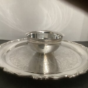 以下が含まれることがあります： 装飾的なデザインが施された銀製のサービングトレイと、中央に合わせた銀製のボウル