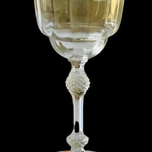 May include: A clear glass wine goblet with a textured stem and base. The goblet has a wide, round bowl and a delicate, fluted design.