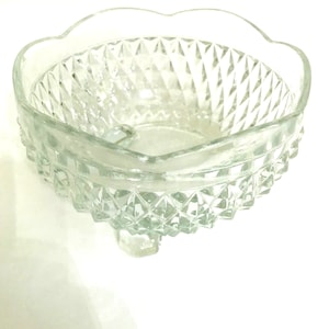 May include: A clear glass bowl with a scalloped rim and a diamond pattern. The bowl sits on three small feet.