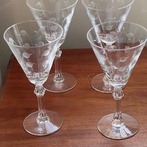 Puede incluir: Juego de cuatro copas de vino de vidrio transparente con un delicado diseño floral grabado. Las copas tienen un tallo alto y delgado y una copa ancha y poco profunda.