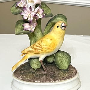 Canary Bird Figurine y Andrea Sadek, Vintage Bird Figurine with Purple Flowers on A Rock