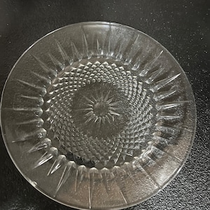 Pode incluir: Um prato de vidro transparente com um padrão de diamante e um design de estrela ao redor da borda.