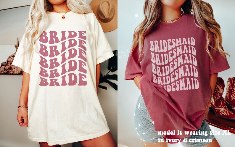 May include: An ivory t-shirt with the word BRIDE printed in a repeating wavy dark pink font and a crimson t-shirt with the word BRIDESMAID printed in a repeating wavy light pink font. The text on the crimson shirt states model is wearing size XL.