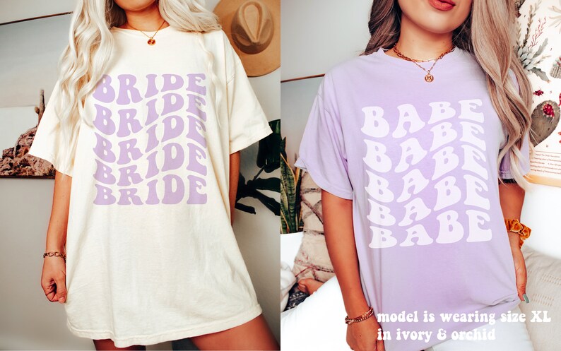 May include: An ivory t-shirt with the word BRIDE printed in a repeating, wavy purple font, and a light purple t-shirt with the word BABE printed in a repeating, wavy white font. The text on the image states model is wearing size XL in ivory & orchid.