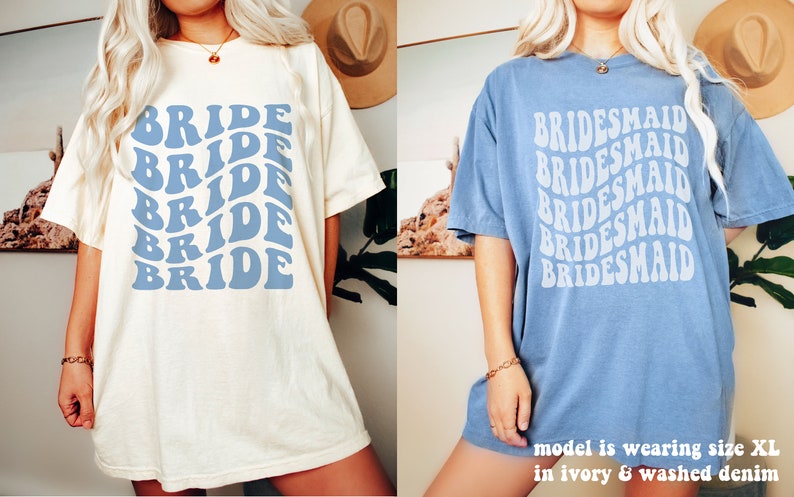 May include: Two short-sleeve crew neck t-shirts. The left shirt is ivory with blue text reading BRIDE in a repeating wavy pattern. The right shirt is washed denim blue with white text reading BRIDESMAID in a repeating wavy pattern.