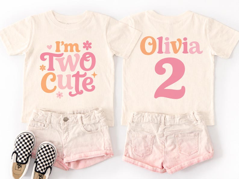May include: Two matching cream-colored toddler t-shirts with the text "I'm Two Cute" and "Olivia 2" in pink and orange. The shirts are paired with pink shorts and black and white checkered slip-on shoes.
