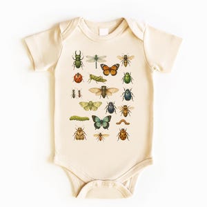 May include: Cream-colored baby onesie featuring a colorful insect illustration. The design includes various bugs like butterflies, beetles, and dragonflies. The onesie has short sleeves and a snap closure at the bottom.