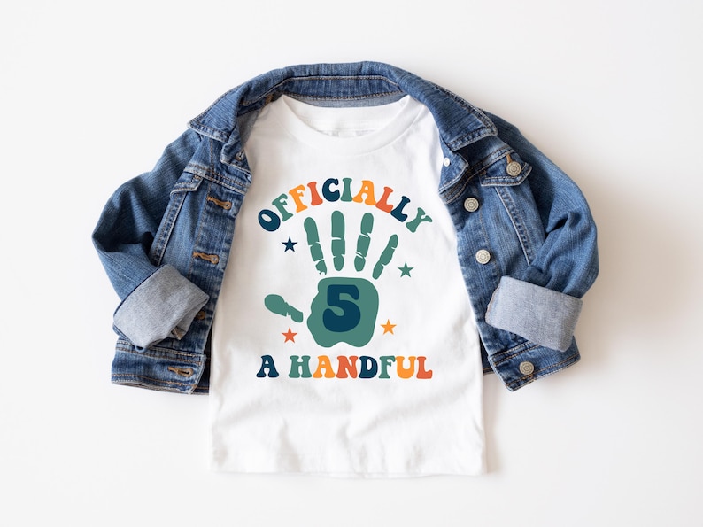 May include: White t-shirt with a colorful graphic that says "Officially 5 A Handful". The graphic features a green handprint with the number 5 inside.