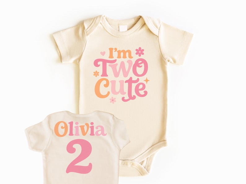 May include: Cream-colored baby bodysuit with the text "I'm Two Cute" in pink and orange. The back of the bodysuit has the name "Olivia" and the number "2" in pink. A cute outfit for a second birthday.