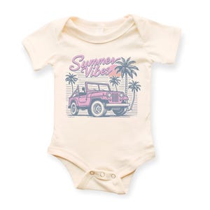 Puede incluir: Un body de beb&eacute; de color crema con un jeep rosa y palmeras. El texto "Summer Vibes" est&aacute; impreso en morado en el body.
