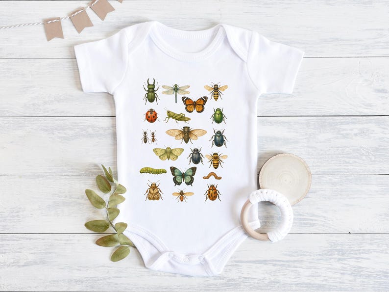 May include: White baby onesie featuring a colorful illustration of various insects, including butterflies, beetles, and ants. The design is printed on a soft, short-sleeved bodysuit, perfect for a baby.