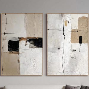 Puede incluir: Dos pinturas abstractas enmarcadas. La obra presenta una superficie texturizada con una paleta de blanco, beige, negro y dorado. Las composiciones se dividen por líneas y formas, creando una estética moderna y minimalista.
