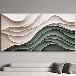 Pode incluir: Arte de parede abstrata com formas onduladas em camadas em tons de branco, bege e verde. A obra de arte é emoldurada em uma fina borda prateada. Está pendurada acima de um sofá branco em uma sala de estar moderna.