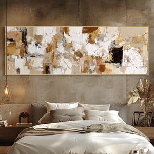 May include: Abstract painting in a gold frame, featuring a textured design in white, beige, brown, and black. The artwork hangs above a bed with neutral-toned bedding, creating a calming atmosphere.