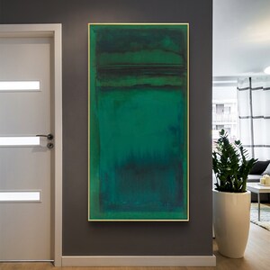 Puede incluir: Pintura abstracta con un esquema de color verde, azul y negro. La pintura est&aacute; enmarcada en un marco dorado y est&aacute; colgada en una pared gris.